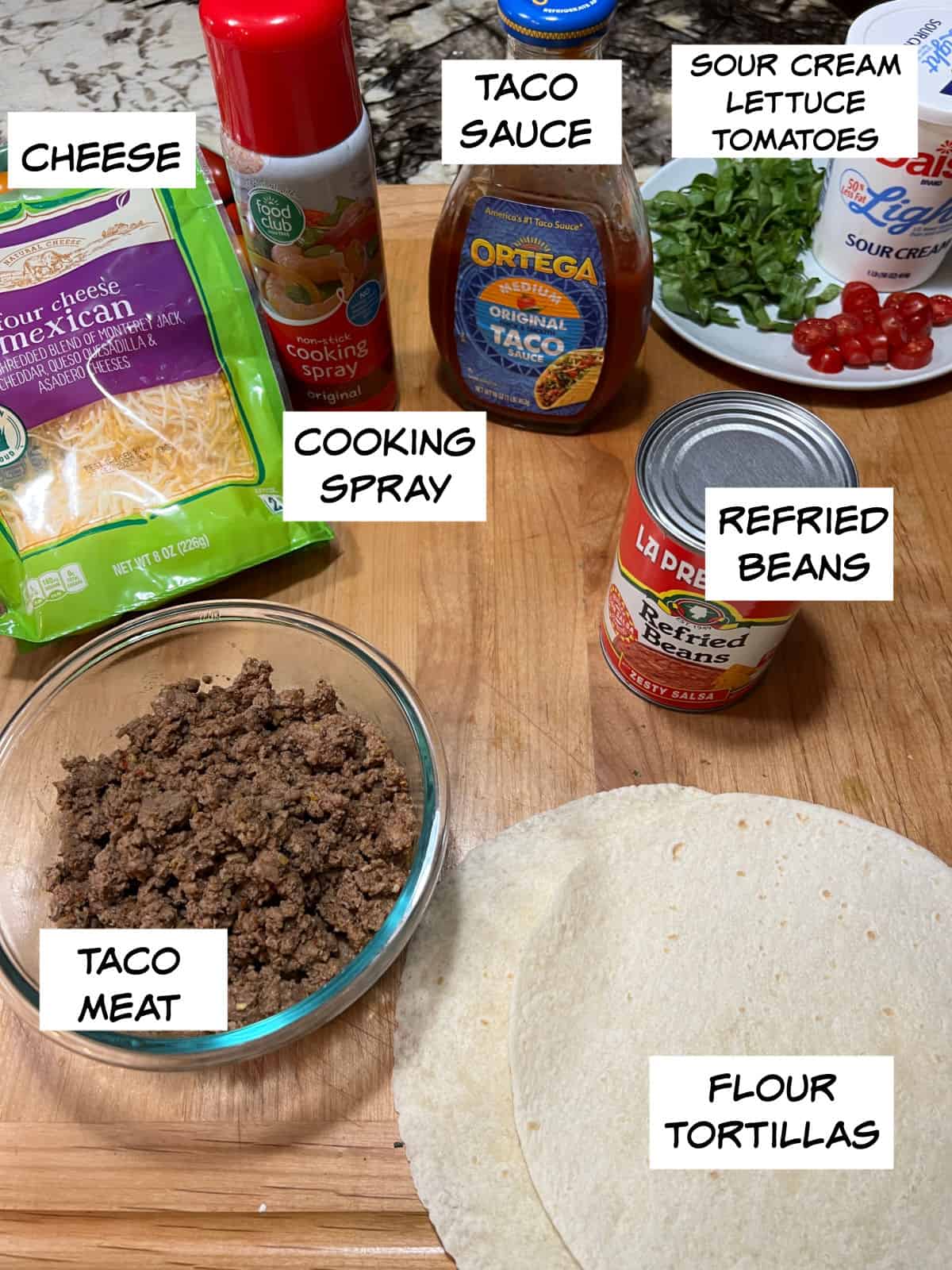 Ingredients: cheese, cooking spray, taco sauce, sour cream, lettuce, and tomatoes, refried beans, flour tortillas, and taco meat.