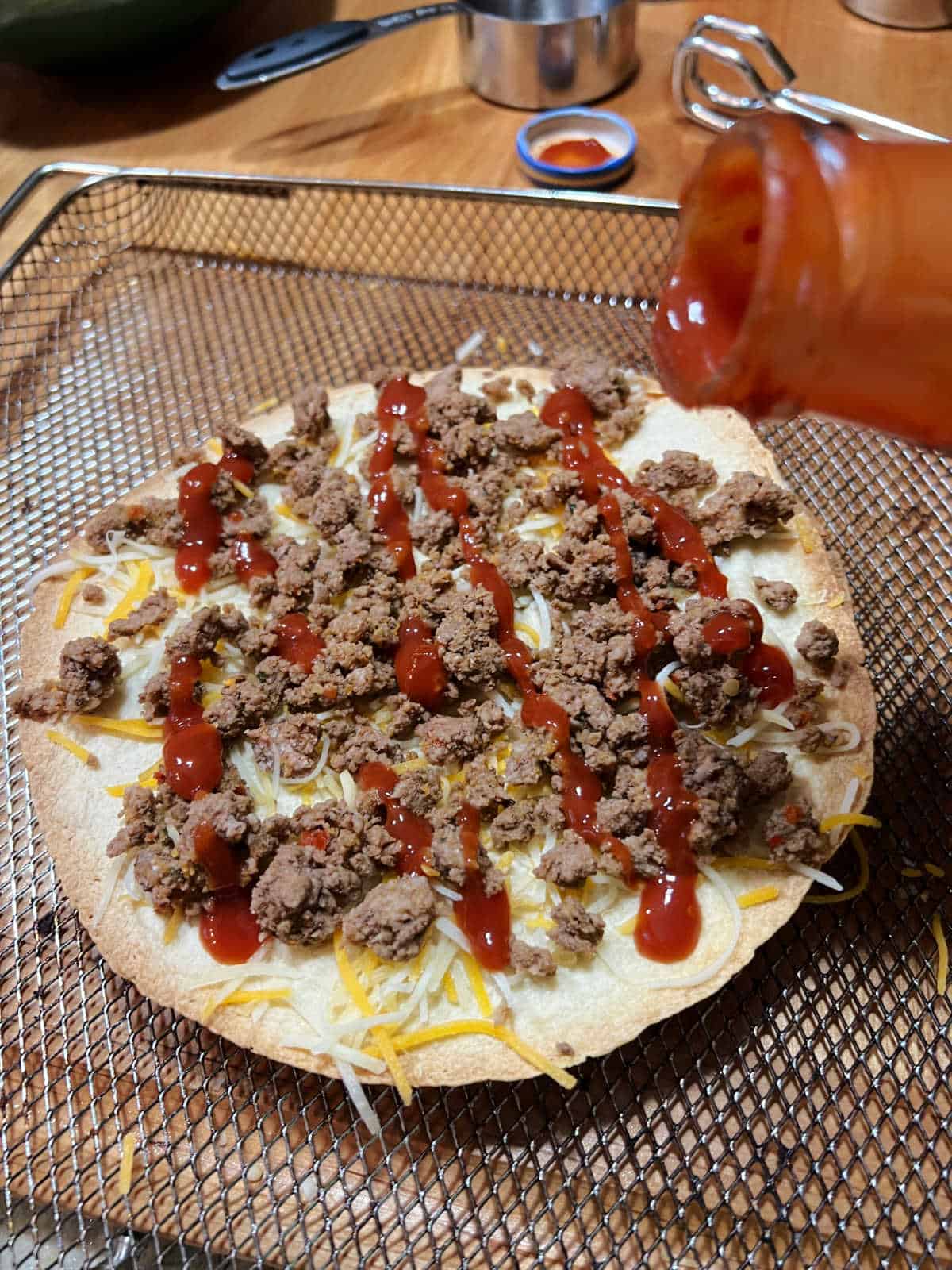 Drizzling taco sauce on the pizza.