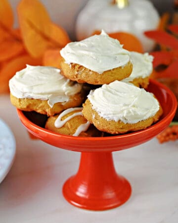 Small dish with a stack of old fashioned pumpkin cookies, frosted with cream cheese frosting and ready to eat!