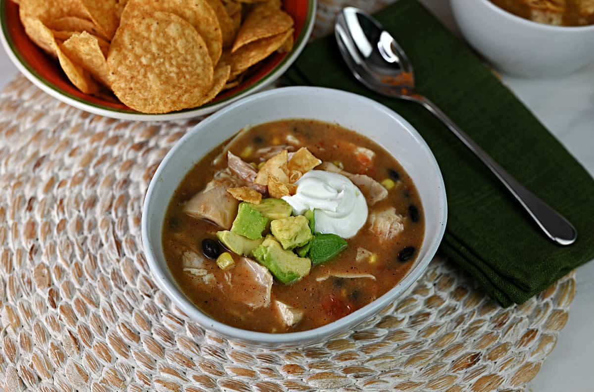 Bowl of chicken tortilla soup made with Rotel, garnished with sour cream and avocado.