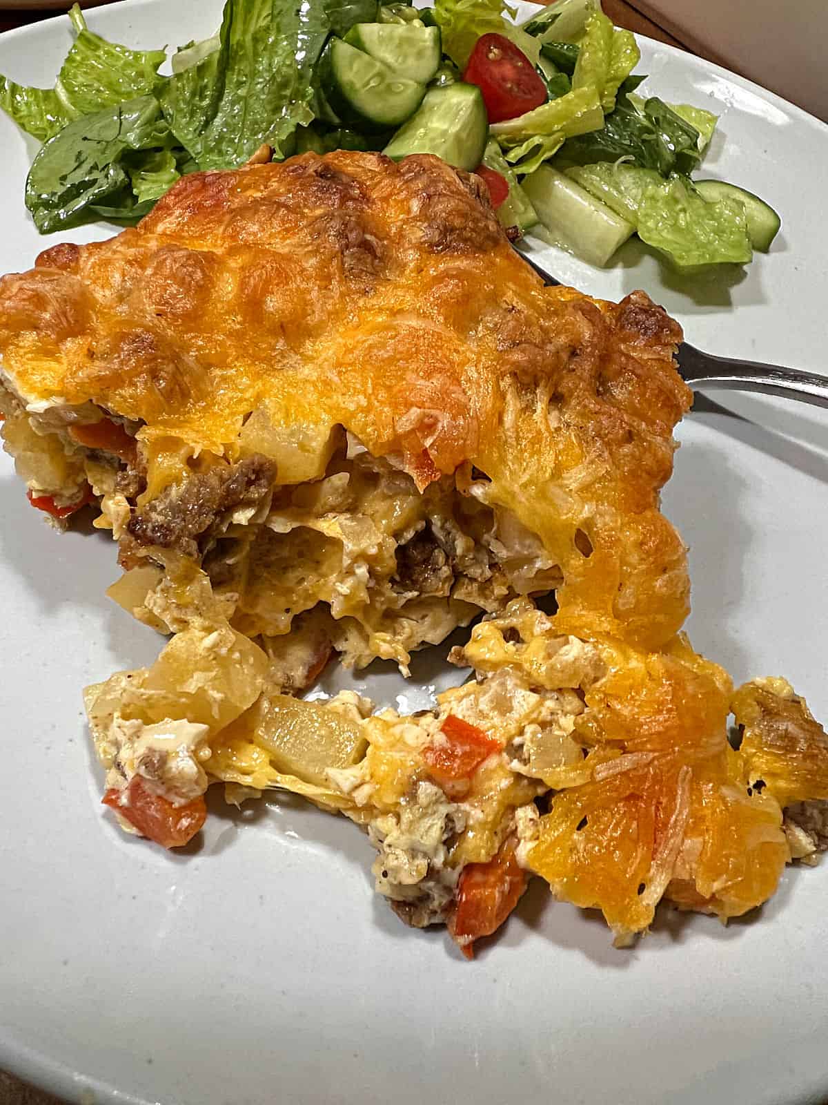 Serving of chorizo egg bake with part broken off, ready to eat.