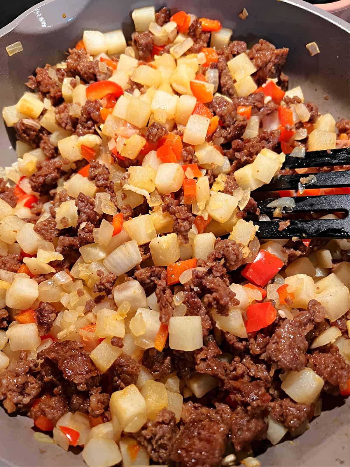 Cooked sausage added to skillet with cooked vegetables.