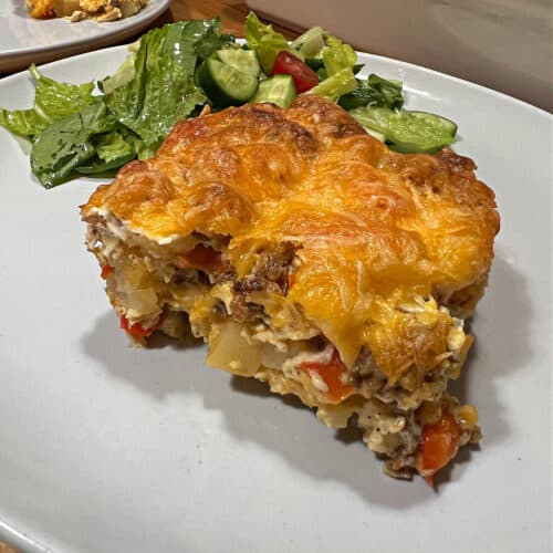 Serving of chorizo egg bake on a plate with a green salad.