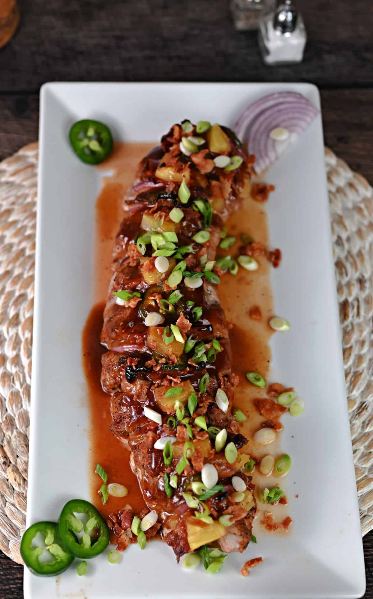 full piece of hasselback pork tenderloin cooked and on a serving platter.