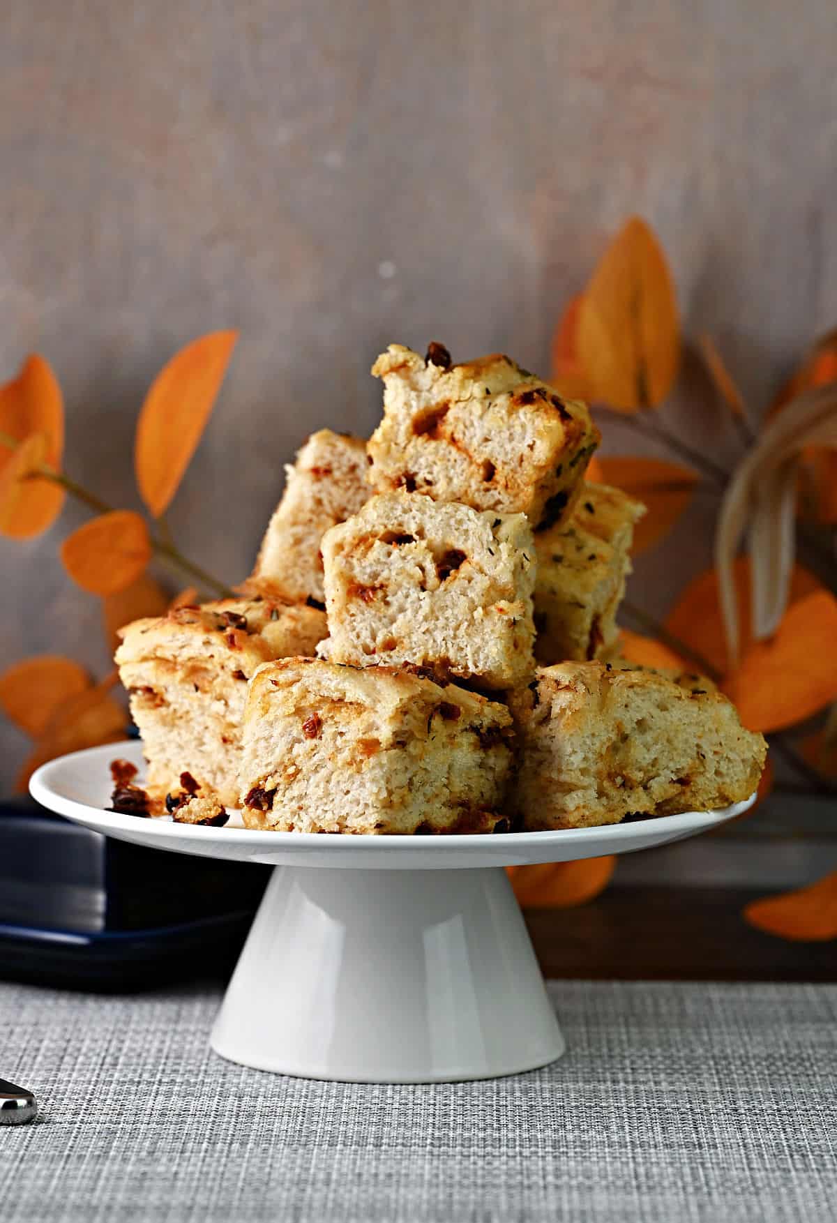 A stack of sun dried tomato focaccia on a footed serving plate.