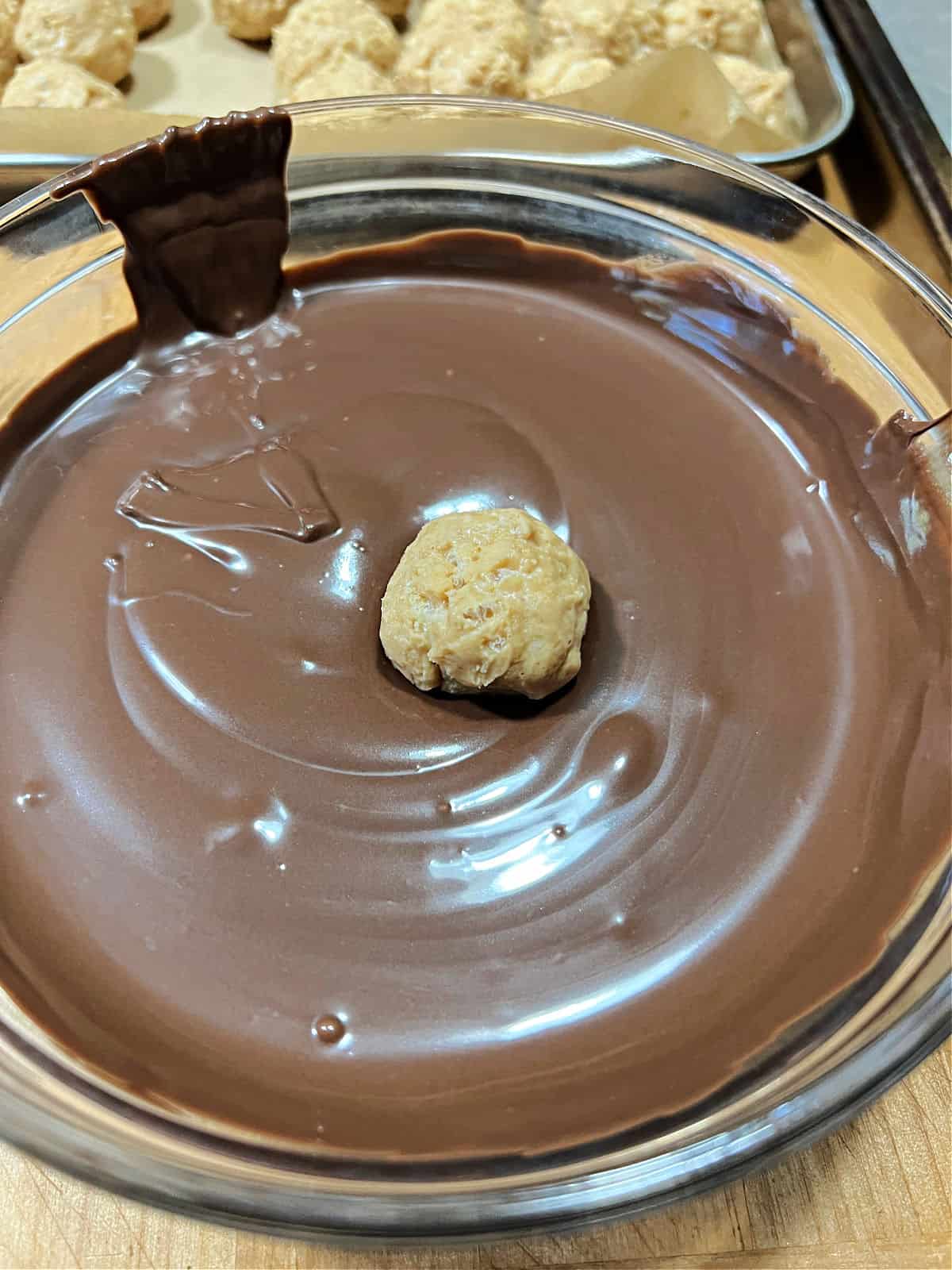 peanut butter ball placed into bowl of melted chocolate.
