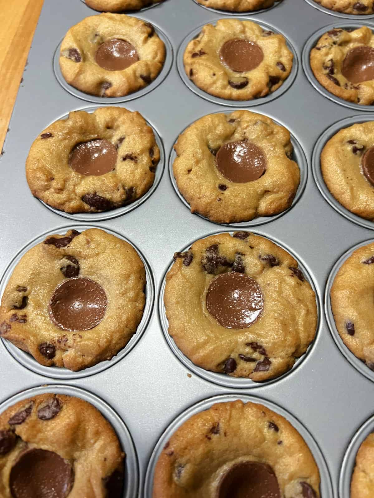 Baked Rolo Cookie Cups cooling in the muffin pan.