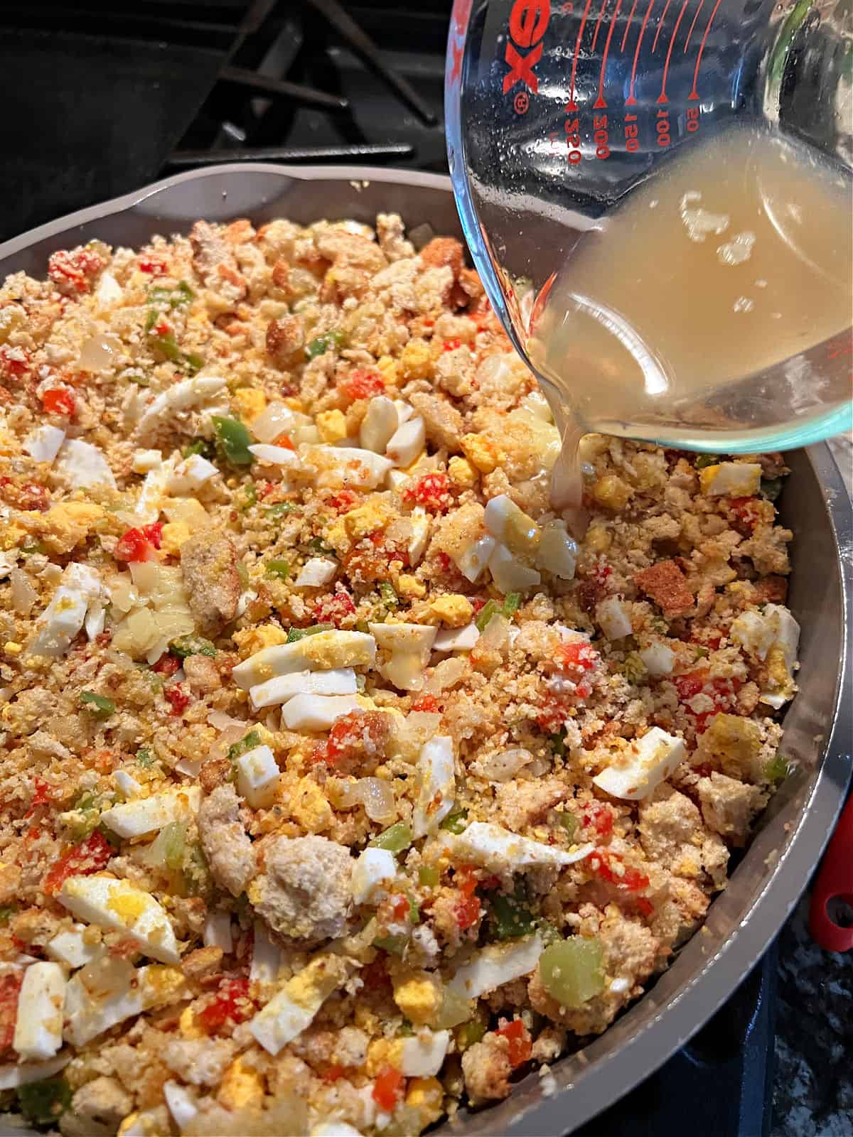 Adding chicken broth to the mixture in the skillet.
