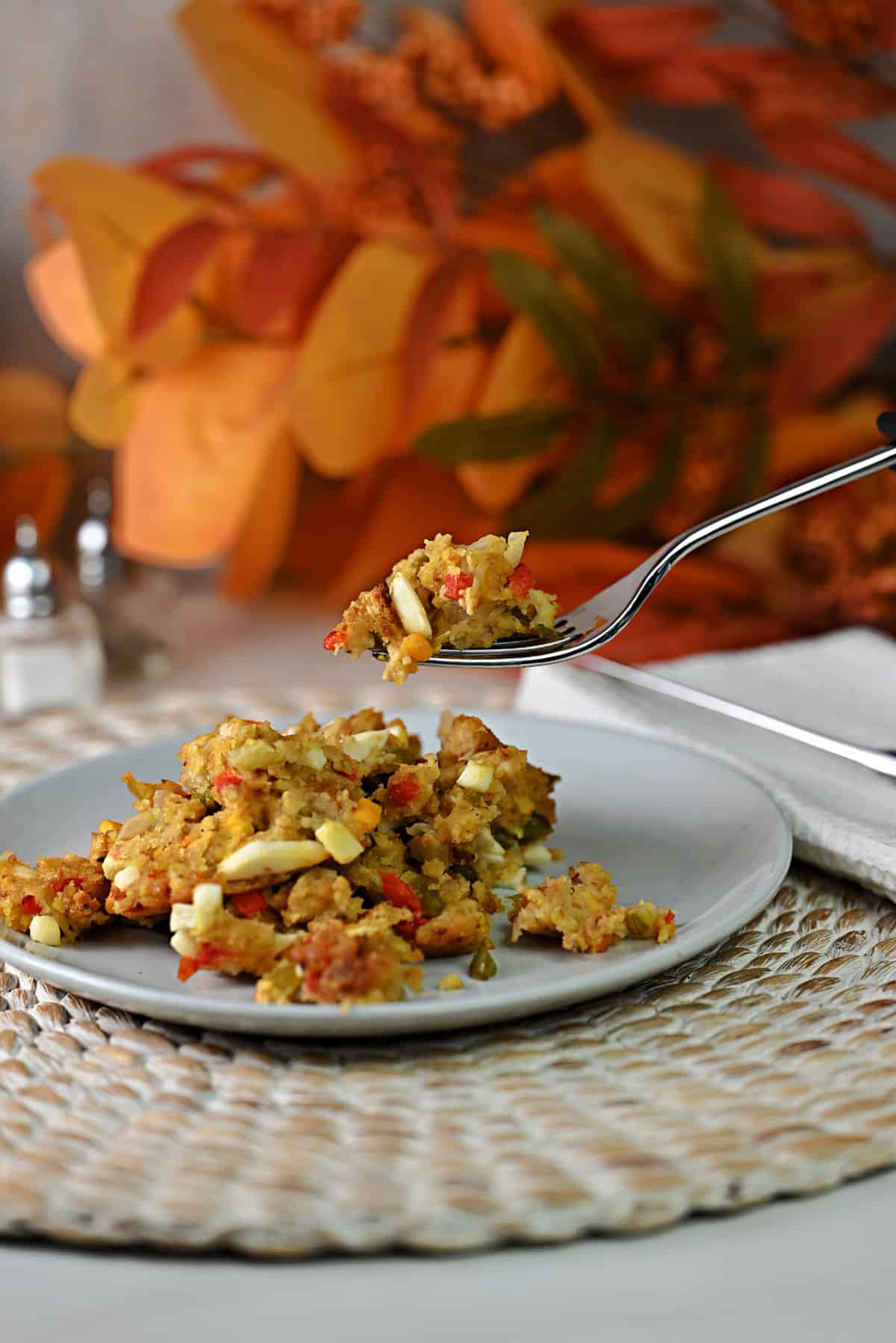 Forkful of cornbread dressing with egg suspended over a plate of the same.