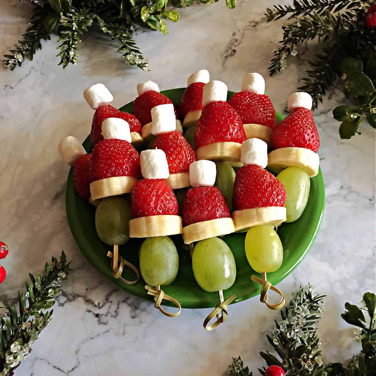 Green plate of grinch kabobs made of fruit.