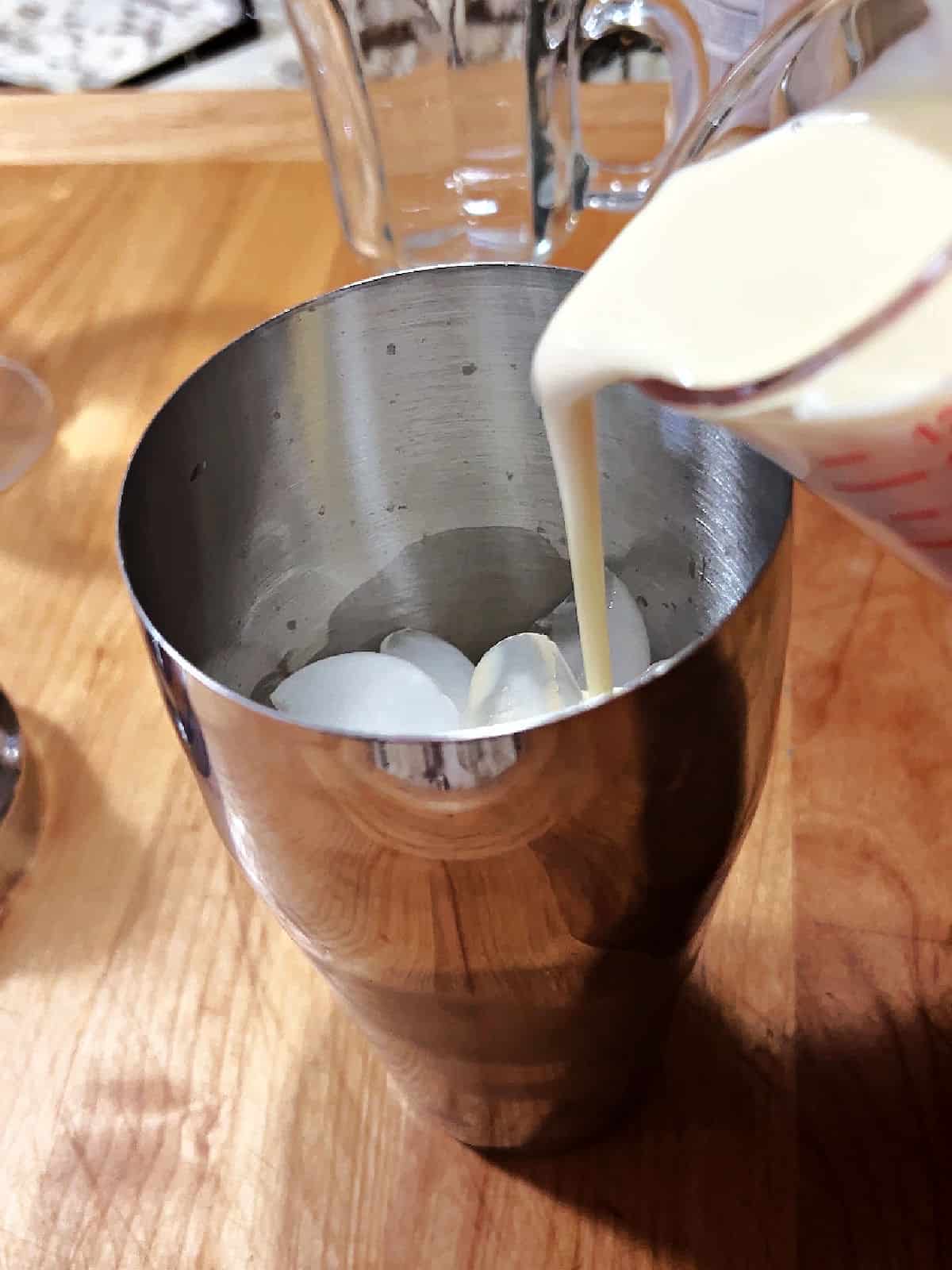 Adding ingredients to cocktail shaker filled with ice.