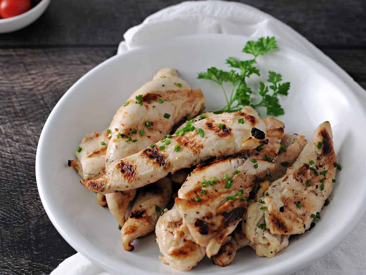 a bowl of healthy chicken tenderloins cooked on the grill.