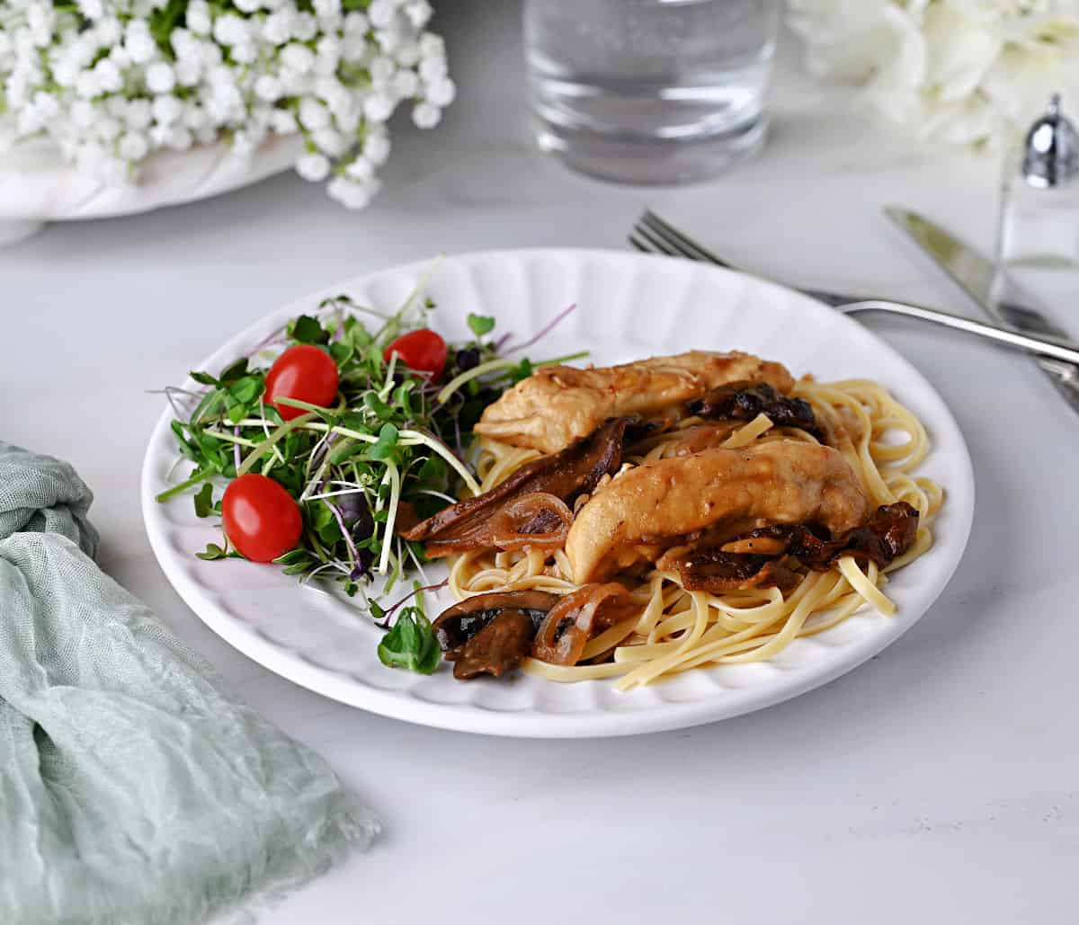 Chicken marsala on fettuccini noodles and a small salad on the side.