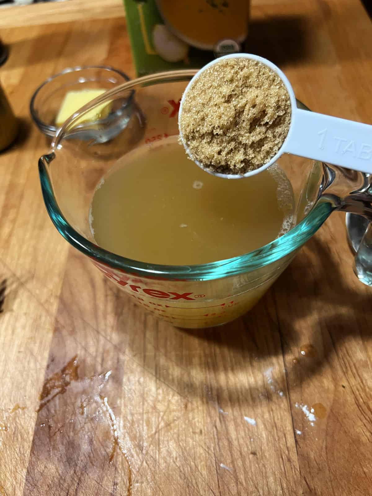 Adding ingredients to broth in measuring cup.