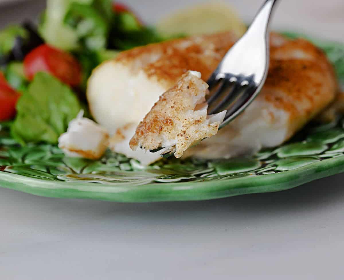 Forkful of cooked cod ready to eat.