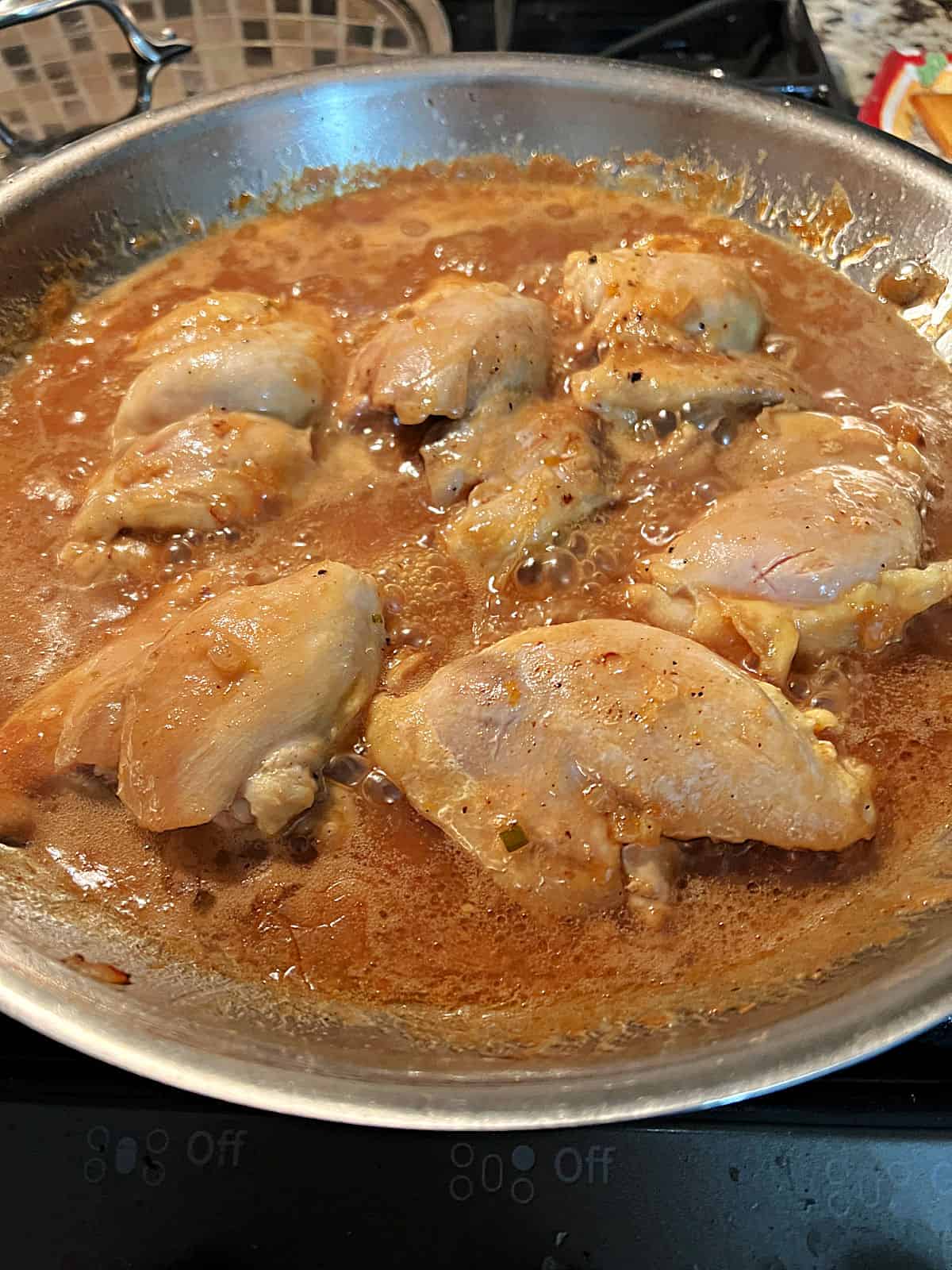 Chicken and sauce cooking together in the skillet.