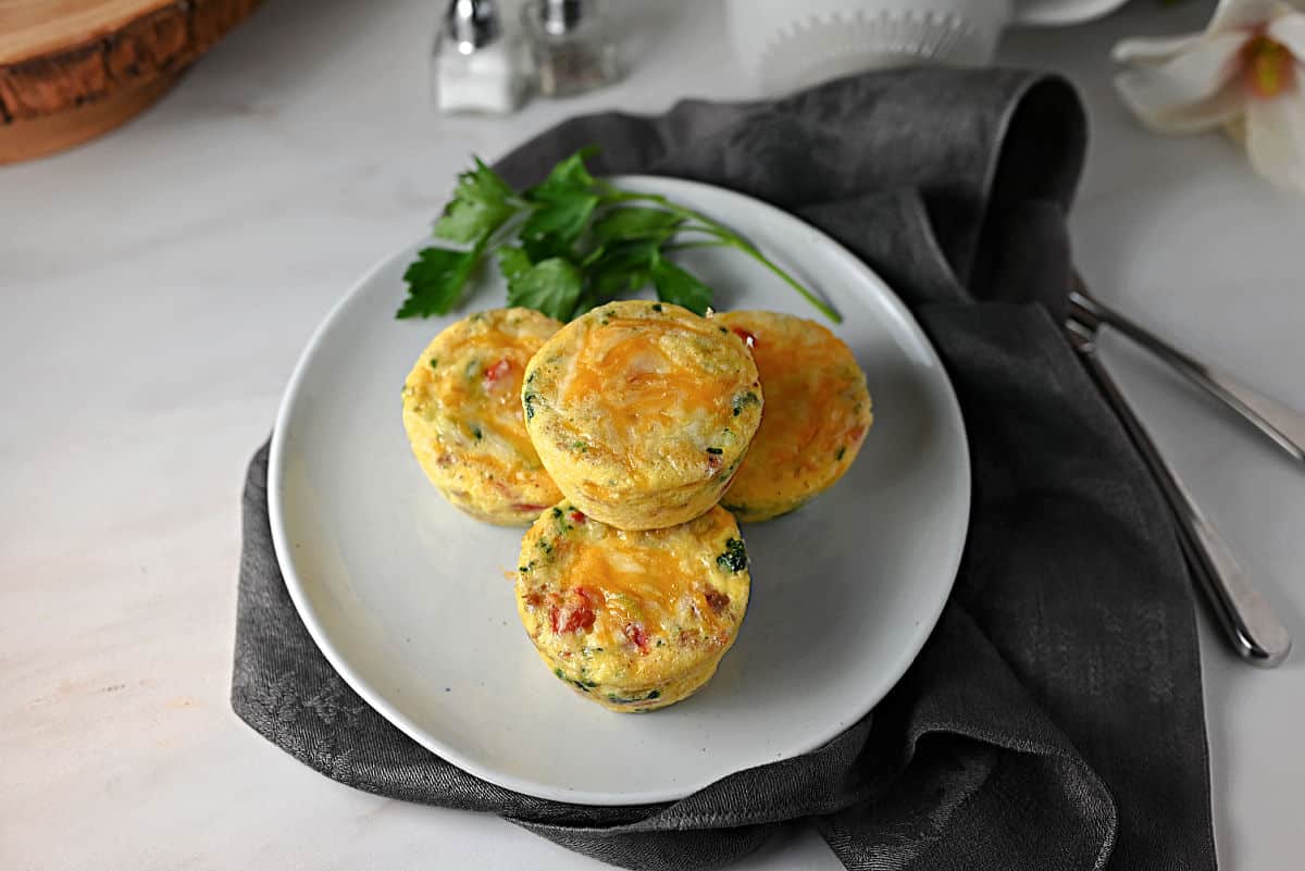 group of cheese sausage and egg bites on a small white plate.