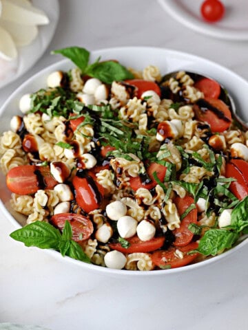 Caprese pasta salad drizzled with balsamic glaze and ready to serve.