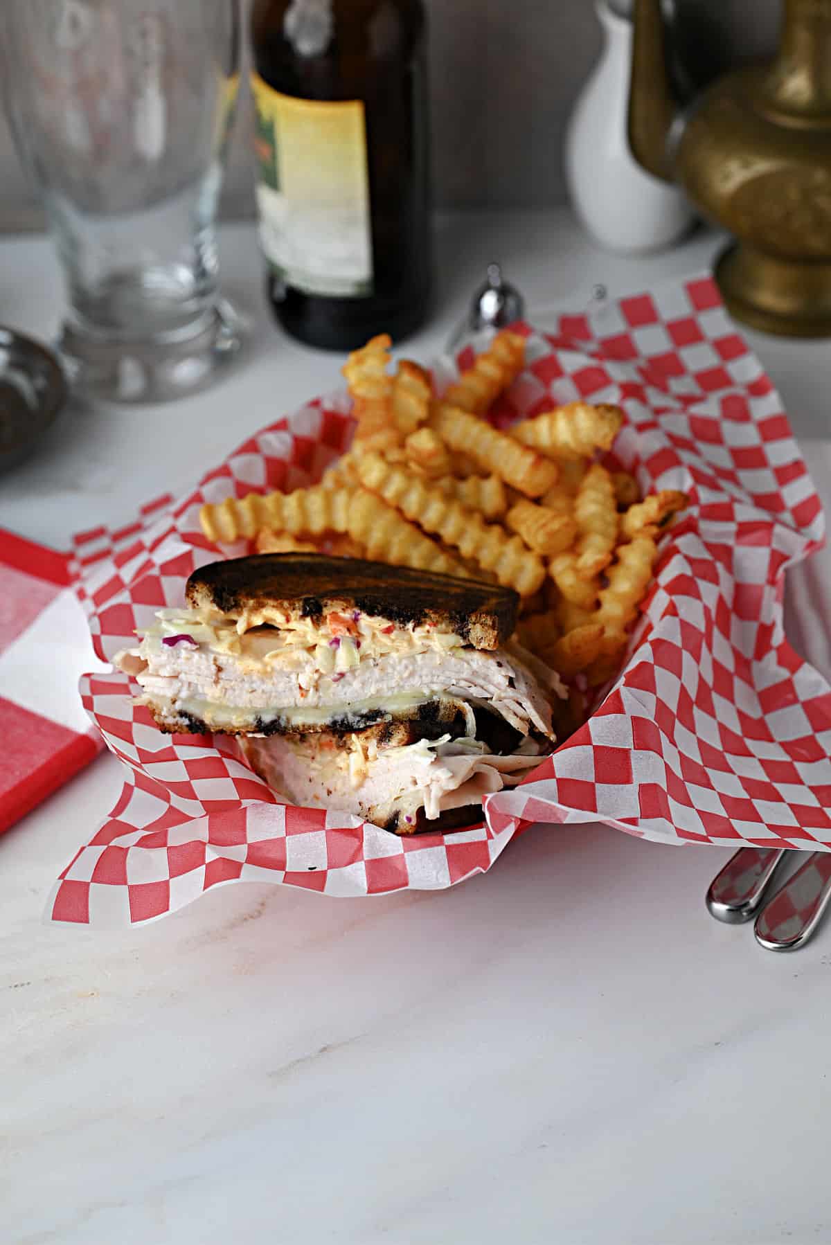 Grilled turkey Reuben (Rachel sandwich) served with fries in a deli style basket.