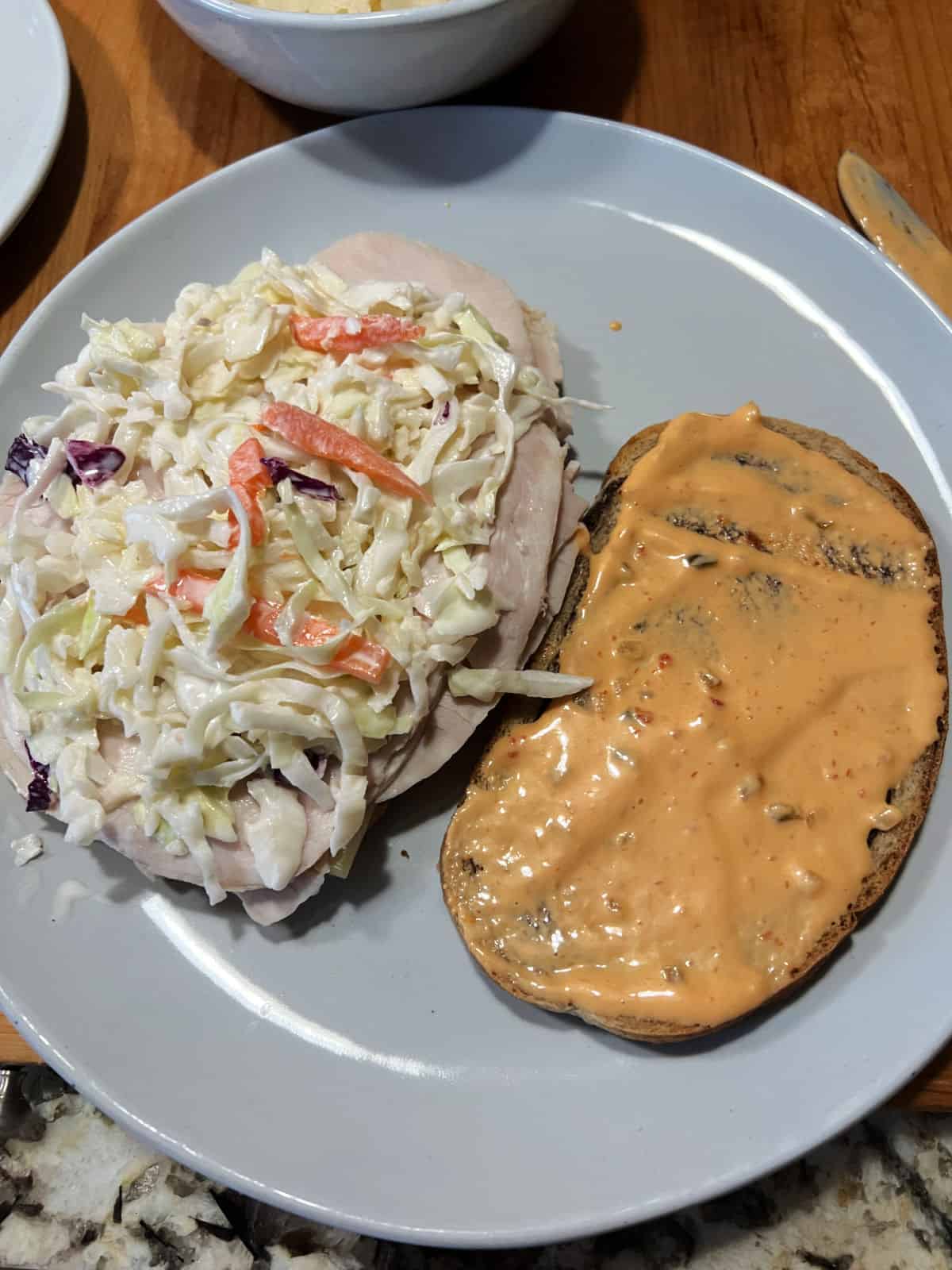 Adding coleslaw to the sandwich.