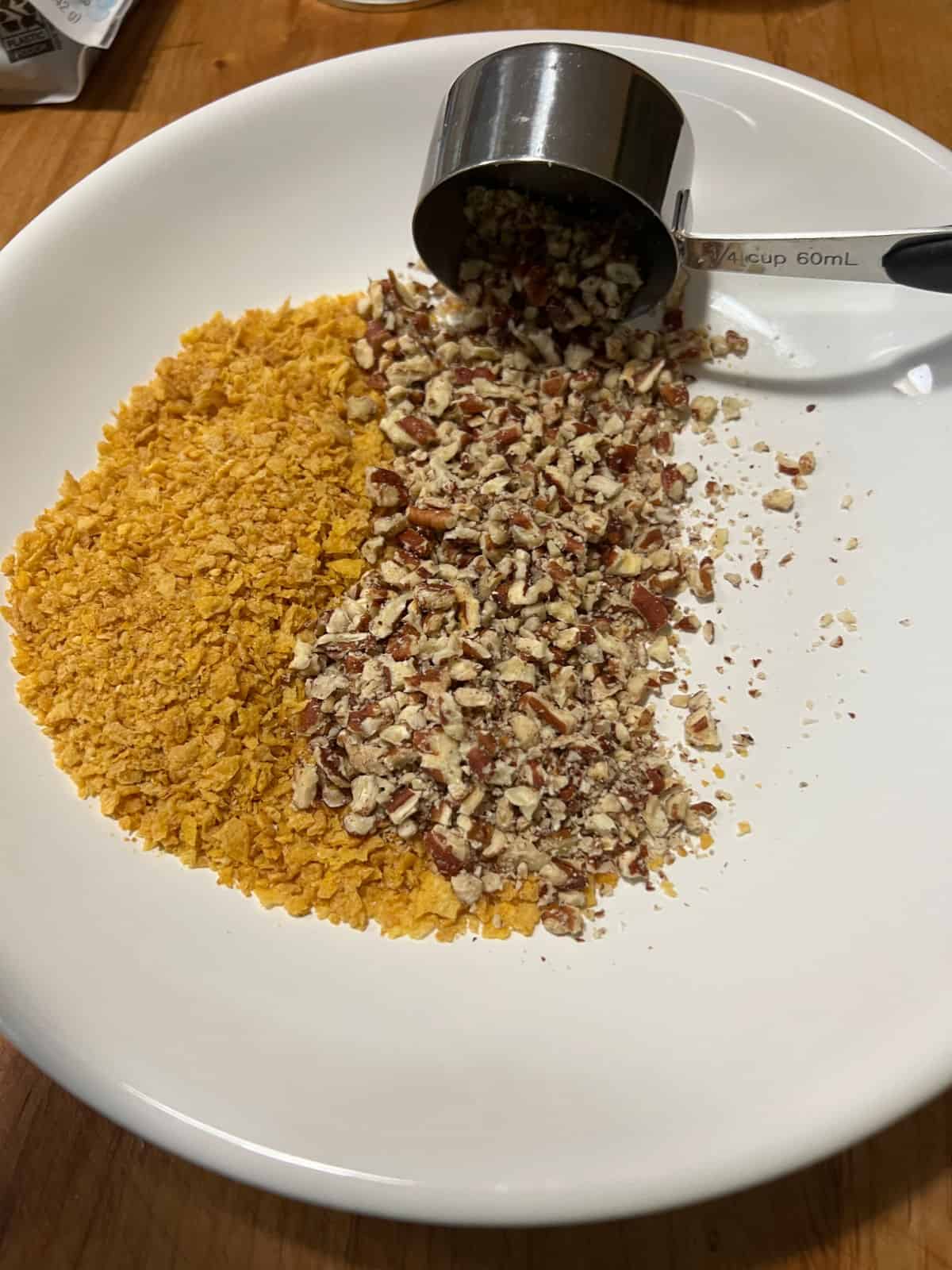 Crushed cornflakes and chopped pecans in a shallow bowl.