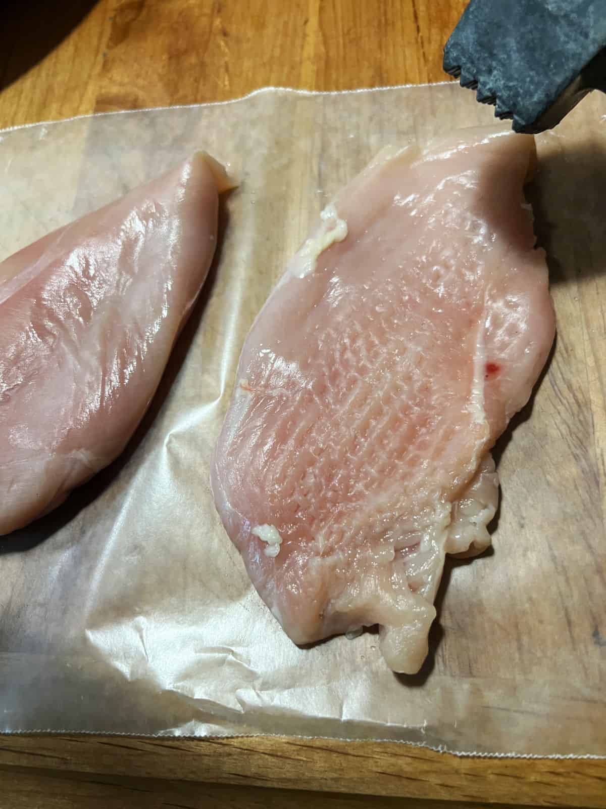 Pounding chicken breasts with a meat mallet.