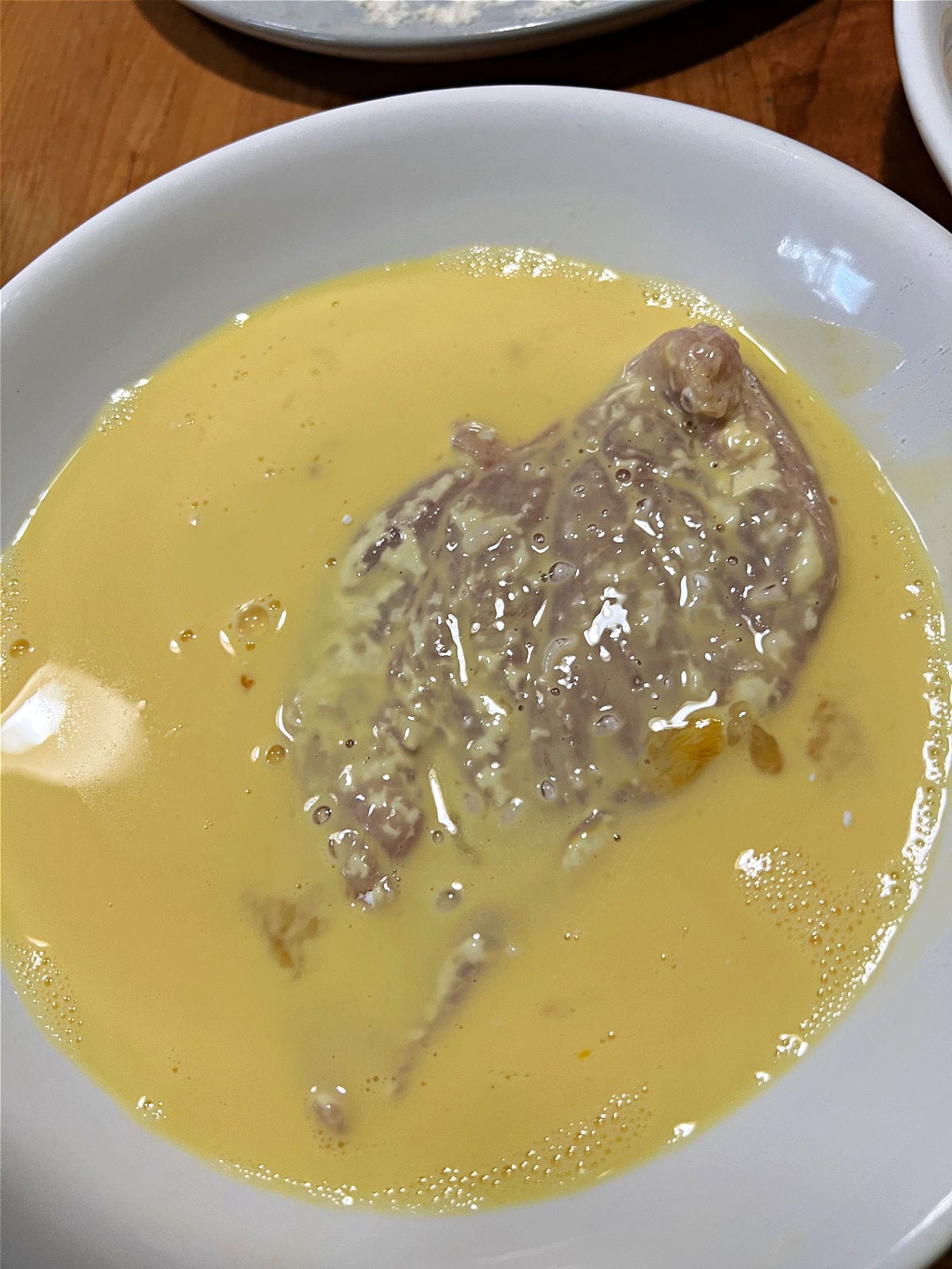 Dipping chicken in egg mixture.