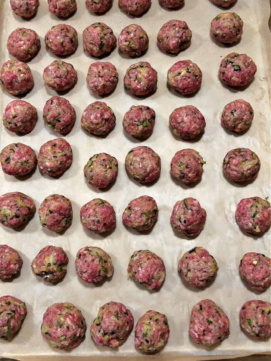 raw meatballs on a baking sheet ready to be baked.