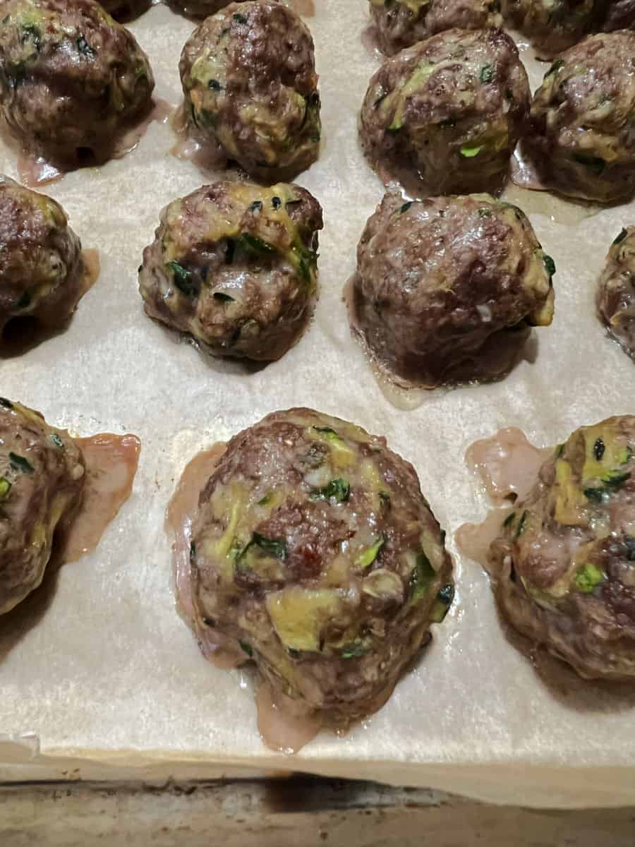 Cooked zucchini meatballs on the baking sheet.