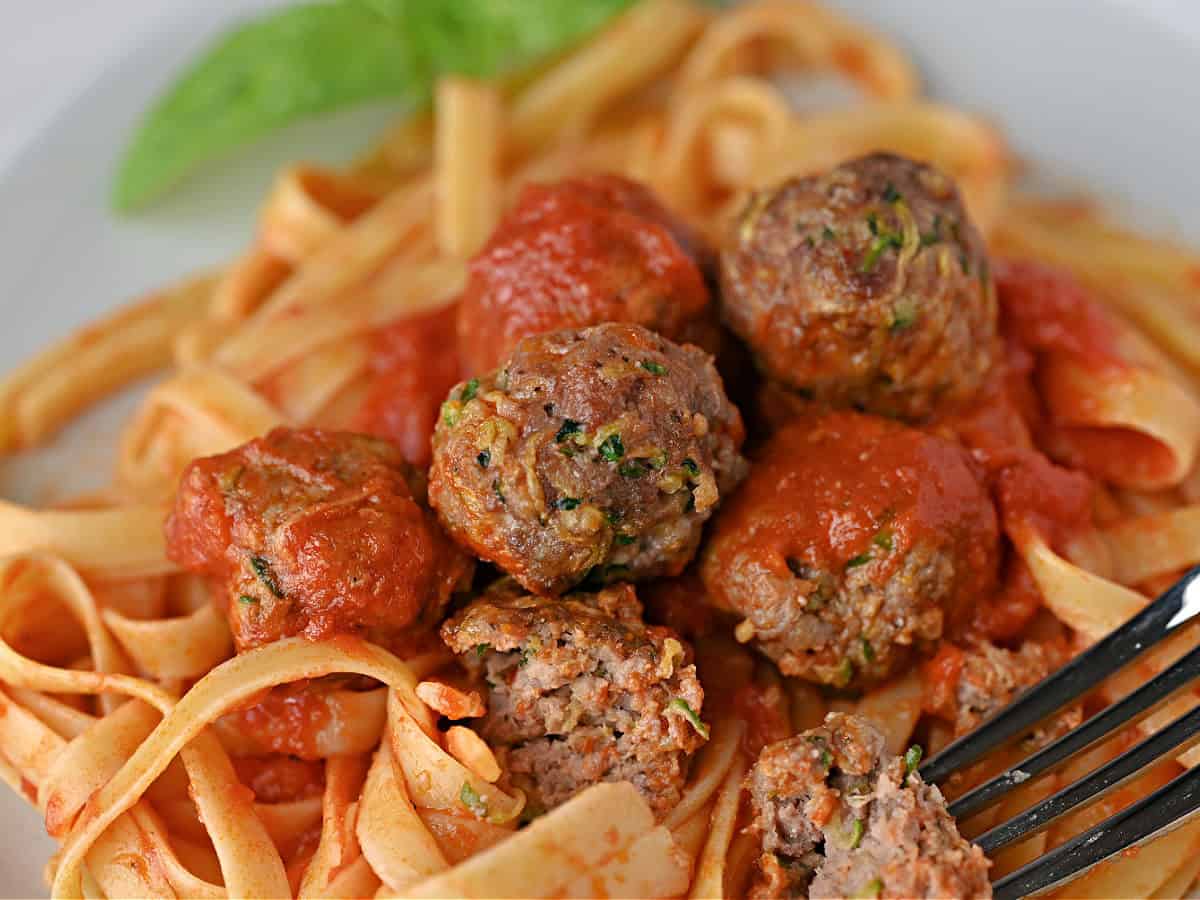 zucchini meatballs in sauce on fettucine noodles.