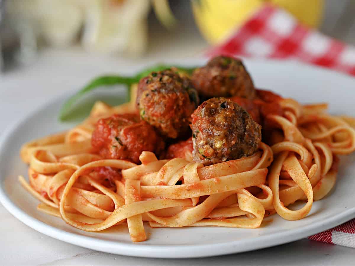 zucchini meatballs in sauce on fettucine noodles.
