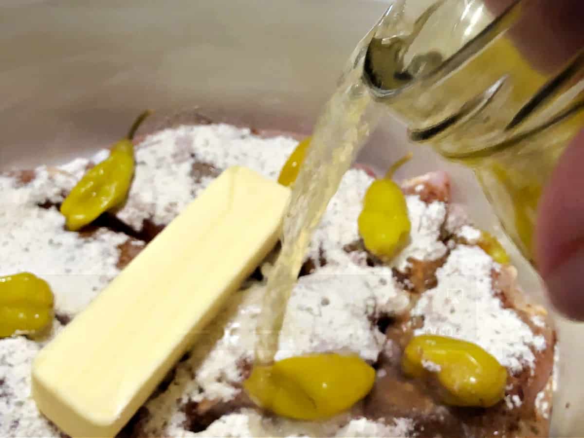 adding pickle juice to the crockpot with butter and peppers.