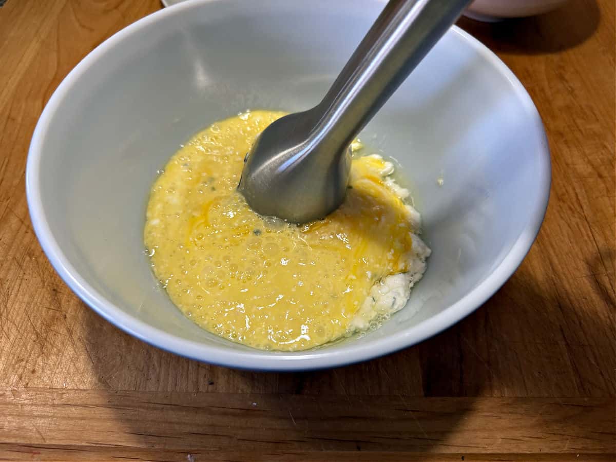 using an immersion blender to combine eggs with cottage cheese.