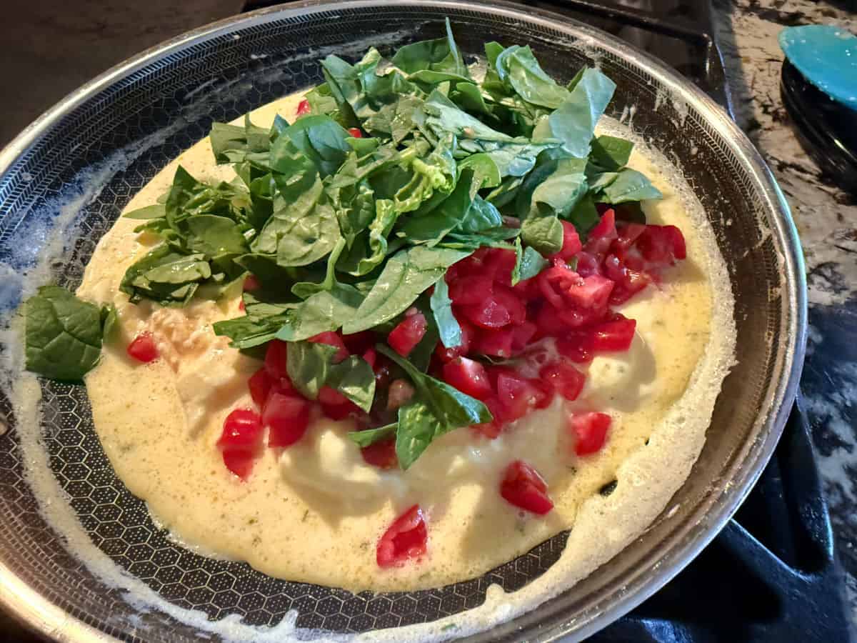 adding veggies to the half cooked eggs.
