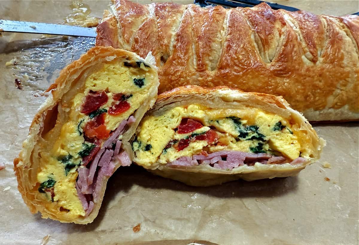 Slices of the breakfast egg bake with the braided puff pastry behind.
