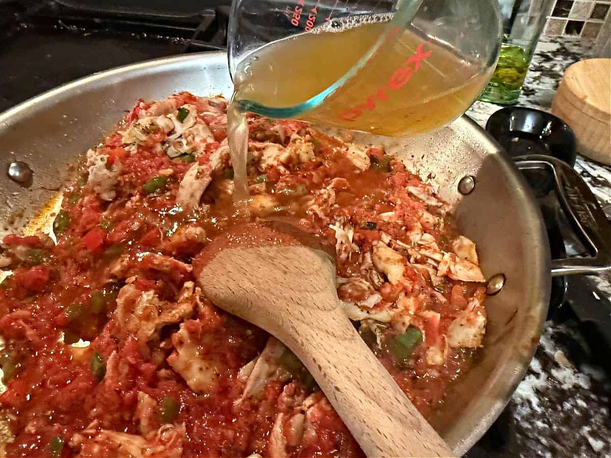 Adding broth to the chicken casserole mixture.