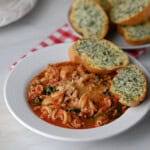 A bowl of turkey lasagna soup with garlic bread.