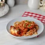 A small plate of spaghetti with pork parmesan and sauce.