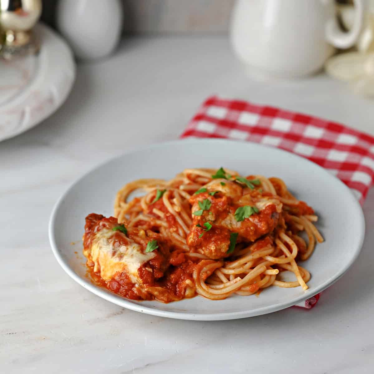 A small plate of spaghetti with pork parmesan and sauce.