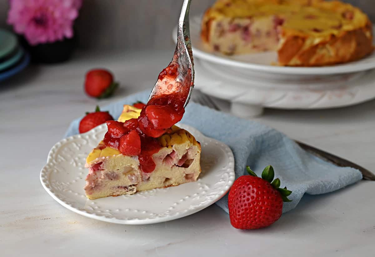 Spoon hold strawberry sauce to put on Greek yogurt cake.