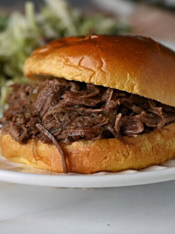 a burger bun filled with shredded beef cooked in a slow cooker, ready to enjoy.