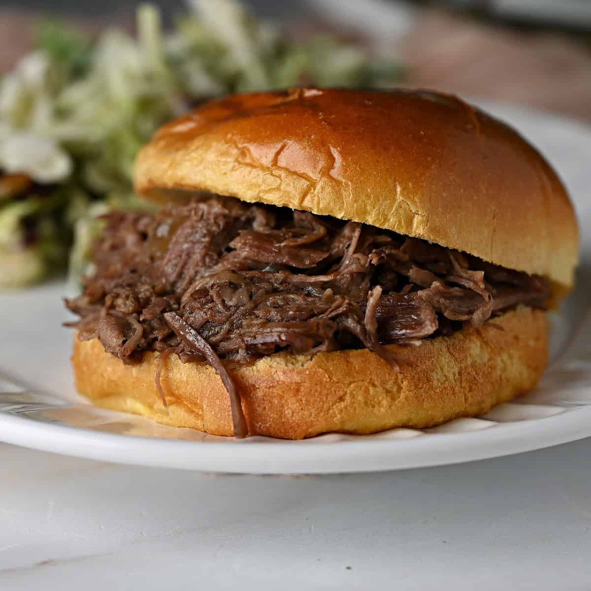 a burger bun filled with shredded beef cooked in a slow cooker, ready to enjoy.