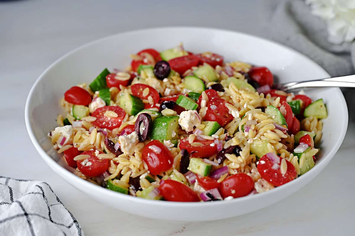 A bowl of Greek orzo pasta salad, full of Mediterranean flavors and ready to serve.