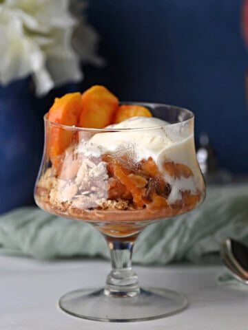 a serving of easy peach crisp with a scoop of vanilla ice cream.