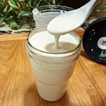 a spoon drizzling the homemade blue cheese dressing over a jar.