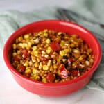 a red bowl full of skillet roasted corn.