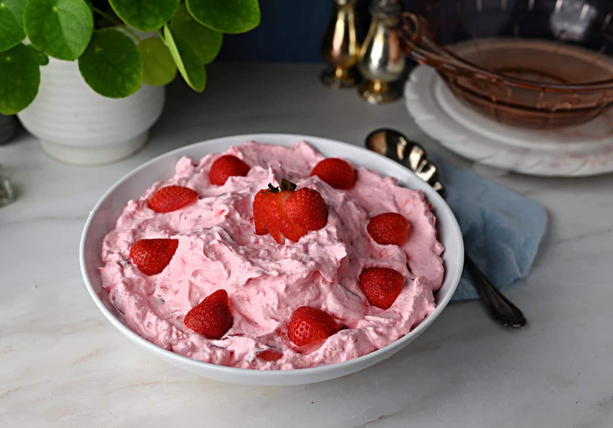 a bowl of strawberry fluff salad garnished with strawberries and ready to serve.