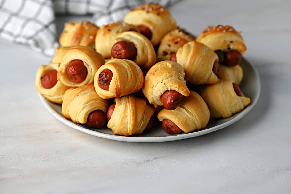 a plate of baked pigs in a blanket ready to serve.