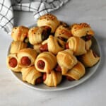 a plate of pigs in a blanket: crescent roll-wrapped cocktail sausages ready for game day noshing.