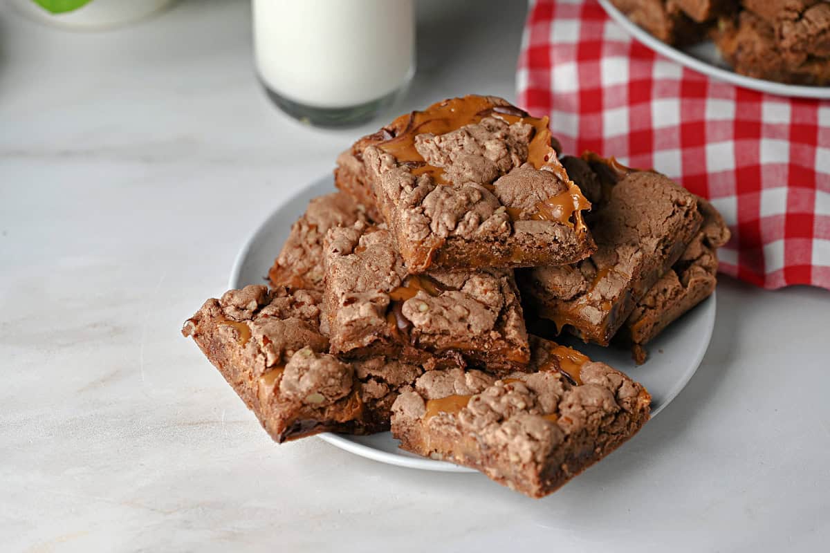 a plate of caramel brownies with a glass of milk.